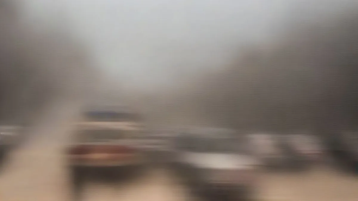 Morning commuters on a hazy New Delhi street under pollution control measures