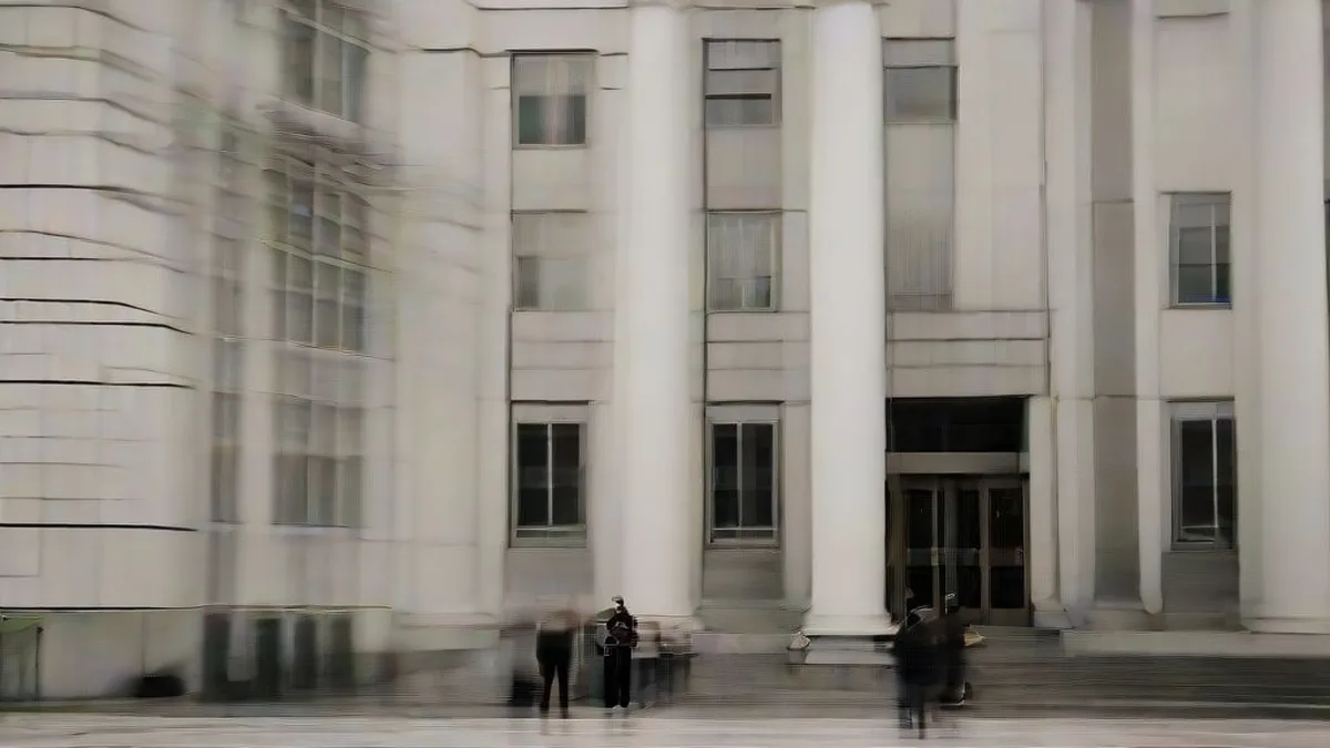 Exterior view of a federal courthouse where media reporters have gathered for legal updates.