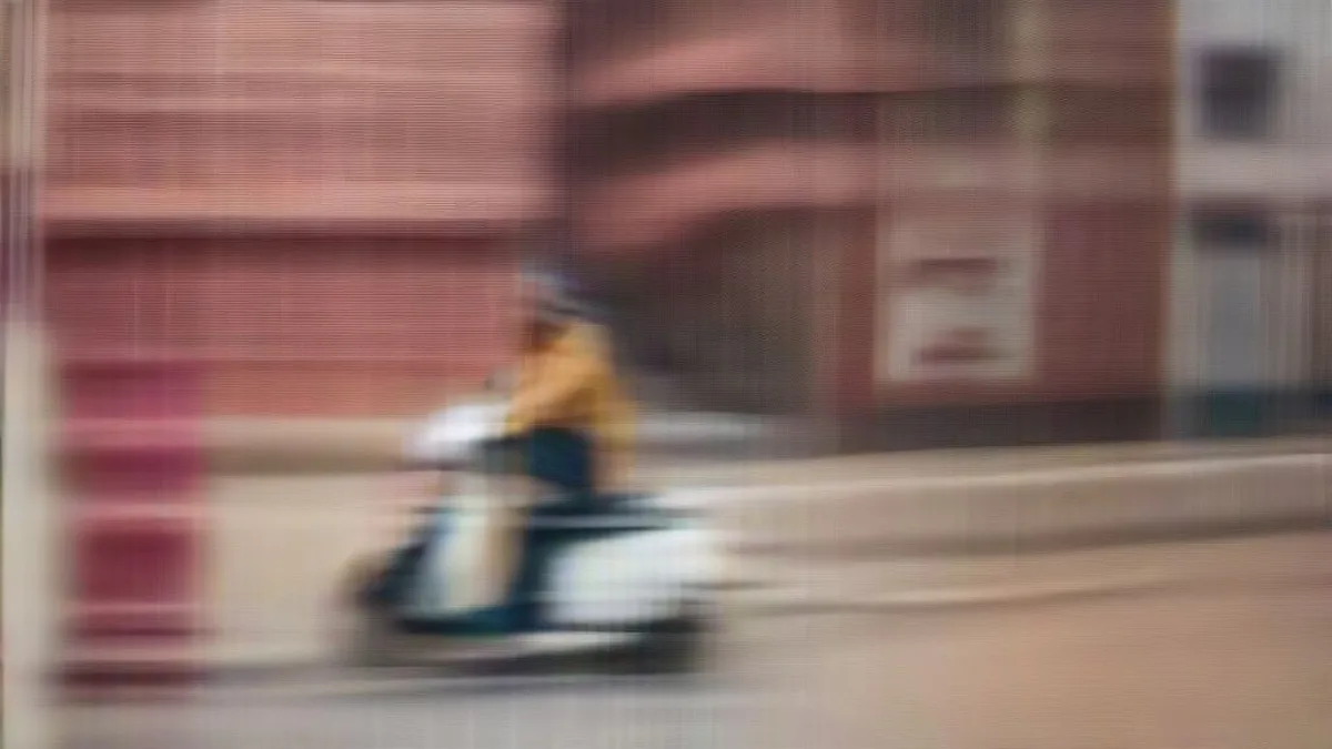 A delivery partner riding a scooter on a busy city street in India.