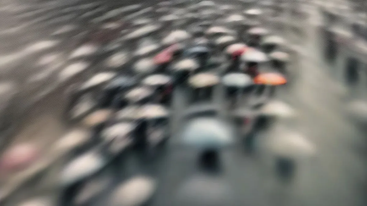 Commuters walking under umbrellas on a gloomy, wet street in New Delhi.