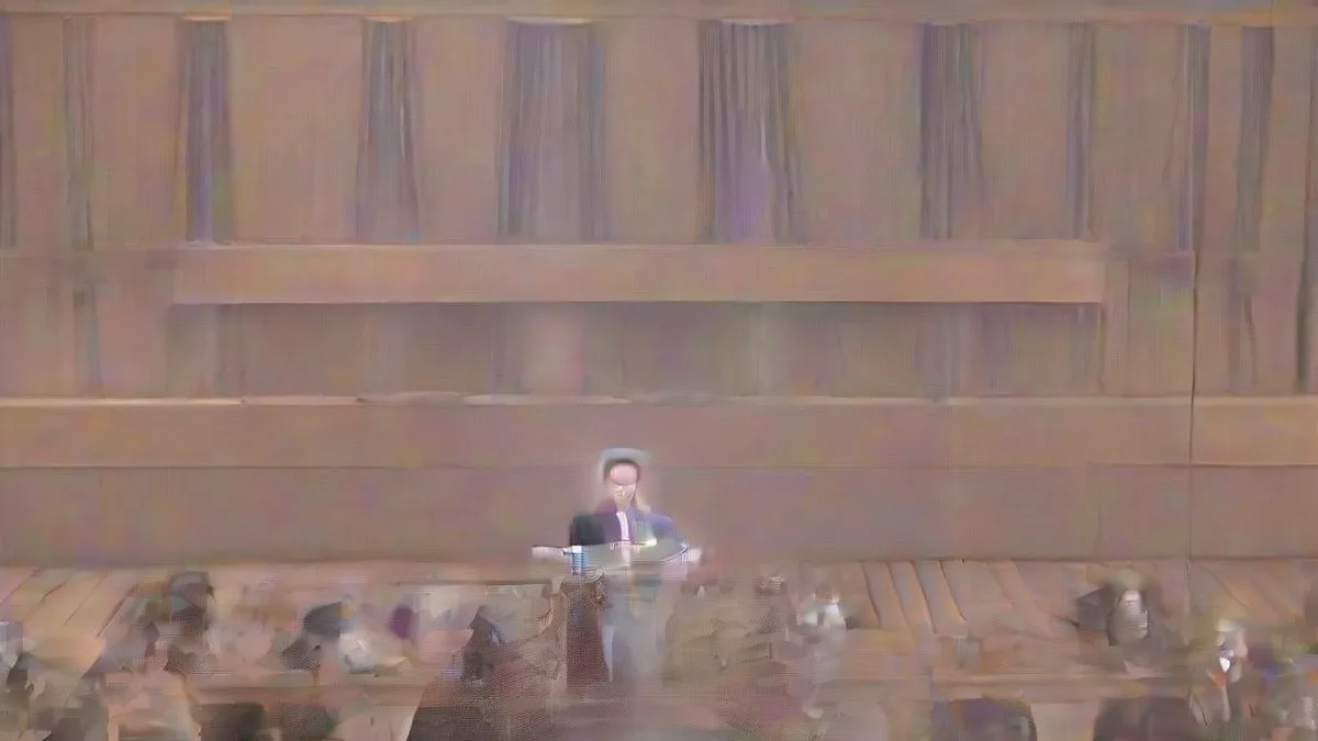 A formal press conference setting with microphones and political figures.
