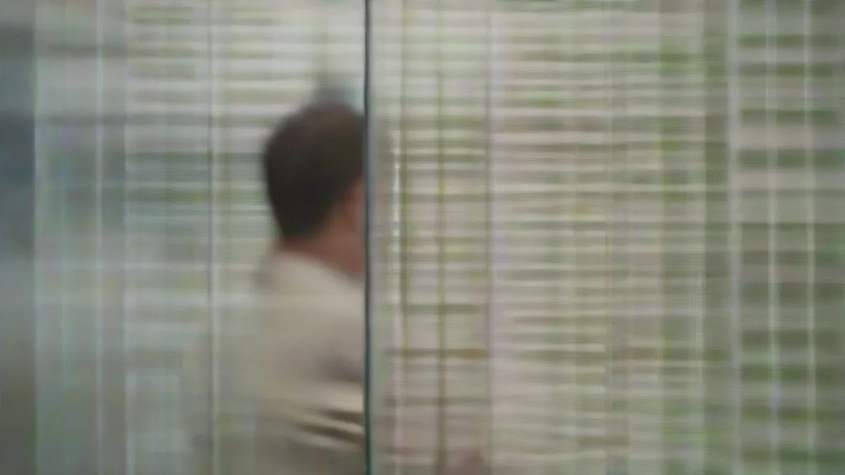 A campaign staffer reviewing digital content on a smartphone in a dimly lit office environment.