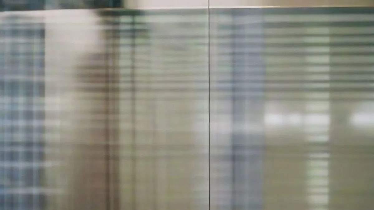 A banking executive reviewing digital security alerts on a mobile device in a modern corporate office.
